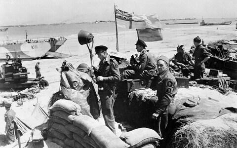 British troops make their way through low water and up the beach after leaving landing craft which transported them across the Channel to the Normandy beachhead  - Credit: BRITISH OFFICIAL PHOTO&nbsp;