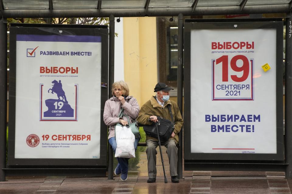 People sit at a bus stop decorated with election posters ahead of the parliamentary election to the State Duma, the Lower House of the Russian Parliament and local parliament in St. Petersburg, Russia, Wednesday, Sept. 8, 2021. In the months before the Sept. 19 parliamentary election in Russia, authorities unleashed an unprecedented crackdown on the opposition, making sure the best-known and loudest Kremlin critics didn’t run. (AP Photo/Dmitri Lovetsky)