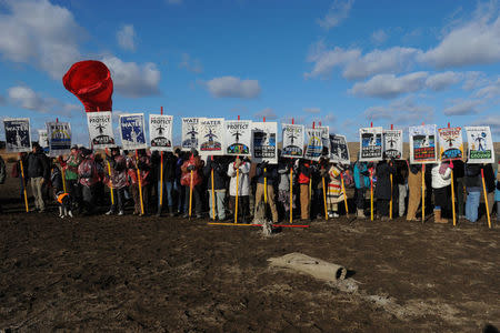 Protesters hold signs during a protest against plans to pass the Dakota Access pipeline near the Standing Rock Indian Reservation, near Cannon Ball, North Dakota, U.S. November 18, 2016. REUTERS/Stephanie Keith