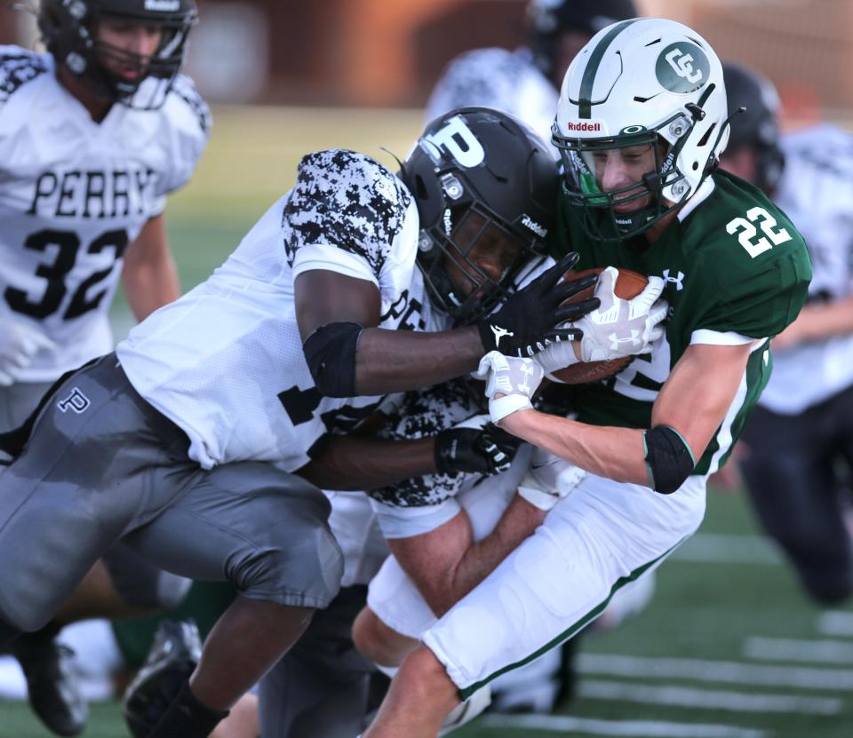 Dan Boron of Central Catholic, right, gets taken down by Samuel Thompson of Perry during their season opening game at Central Catholic on Thursday, August 19, 2021.