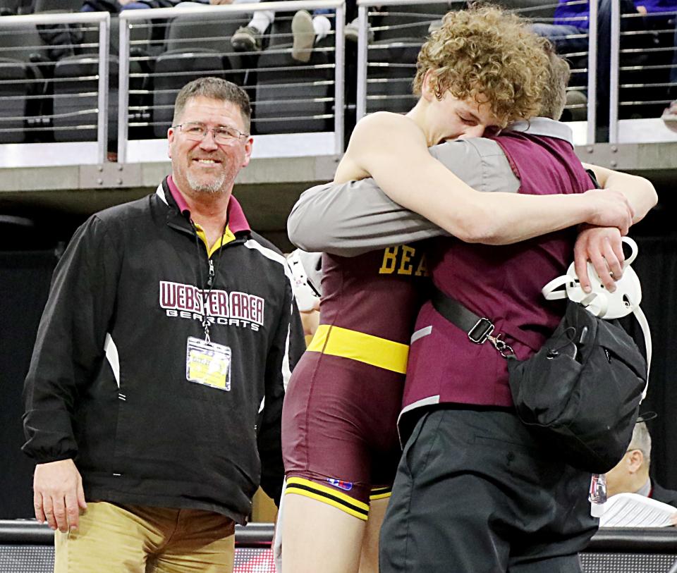Webster Area head wrestling coach Wade Rausch (left) looks on as senior Cael Larson celebrates with his father and assistant coach Beau Larson after the younger Larson won the Class B 138-pound championship in the 2022 South Dakota State Wrestling Tournament at Sioux Falls. Larson ended his career as a four-time state place winner who went 156-28 his last four seasons on the mat.