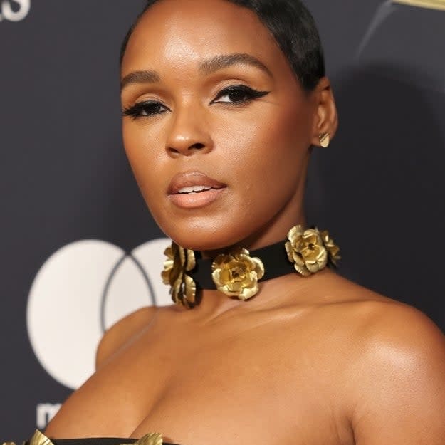 Close-up of Janelle wearing a strapless outfit with gold floral accents and statement earrings