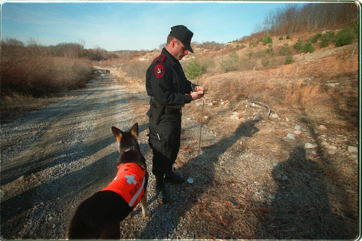 In a 1999 file photo, Rhode Island State Police Trooper Matthew Zarrella reads his compass as he and his trained German shepherd Panzer join the search for a missing person in Westerly.