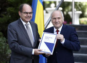 Christian Schmidt, new head of Bosnia's Office of the High Representative, or OHR, left, poses with Valentin Inzko, the outgoing head of OHR, during a ceremony in the capital Sarajevo, Bosnia, Monday, Aug. 2, 2021. Schmidt on Monday took office as the top international official in Bosnia, amid tensions with the country's Serbs who have rejected both his appointment and a ban on genocide denial brought by his predecessor. (AP Photo)