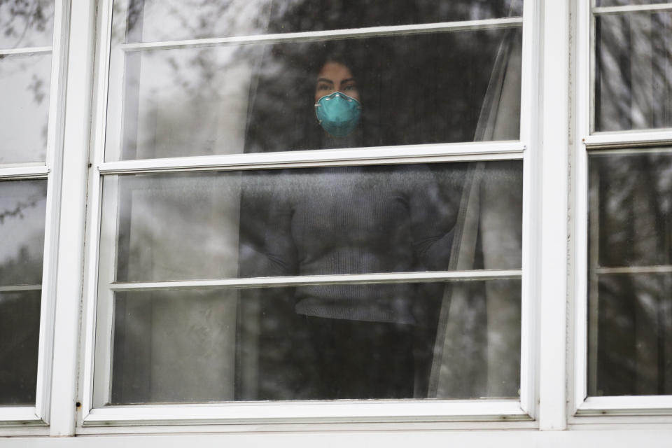 Francy Sandoval looks outside from her home in Melrose Park, Ill., Thursday, April 23, 2020. She works as a receptionist at a community health clinic which treats multiple COVID-19 cases. She has to isolate herself in the attic as soon as she comes home from work each day and is terrified of infecting her family. (AP Photo/Nam Y. Huh)