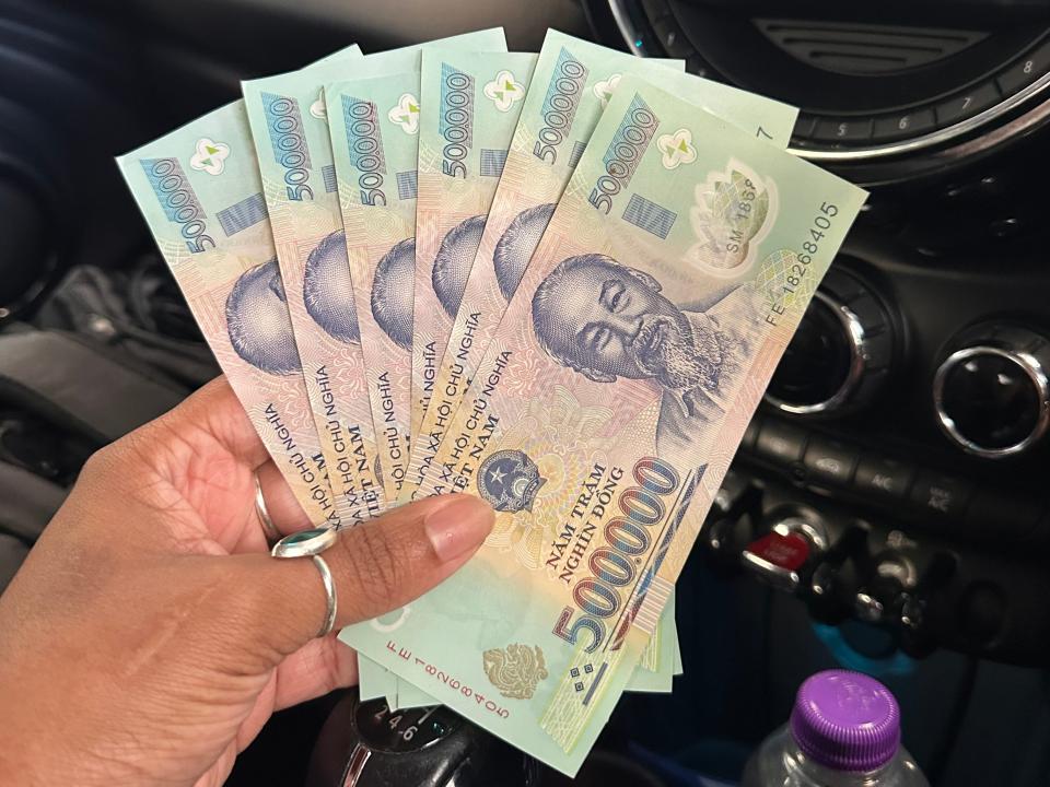 dominique holding up foreign currency in a car