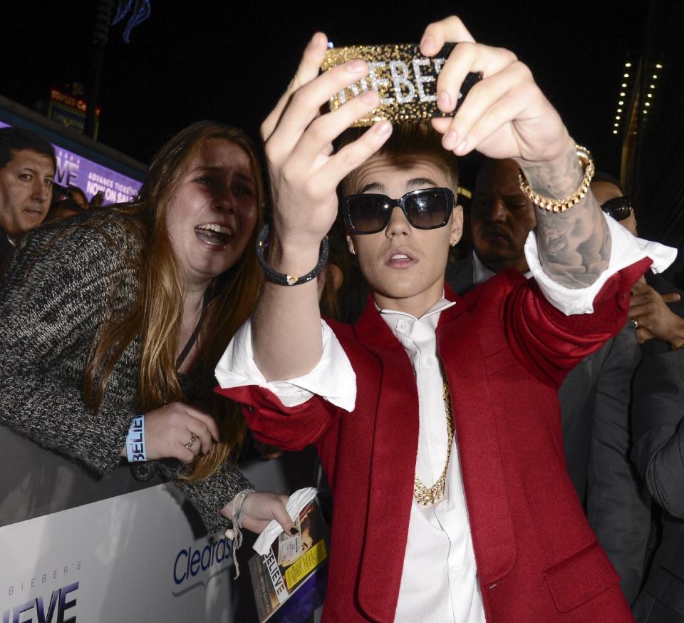 File- In this Dec. 18, 2013 file photo, singer Justin Bieber takes a "selfie" with a fan at the premiere of the feature film "Justin Bieber's Believe" at Regal Cinemas L.A. Live in Los Angeles. The word selfie is on a list of among those words selected for elimination in Michigan's Lake Superior State University's 39th annual batch of words to banish due to overuse, overreliance and overall fatigue. Others include "twerking," "Mr. Mom" and "on steroids." (AP Photo/Dan Steinberg, Invision)