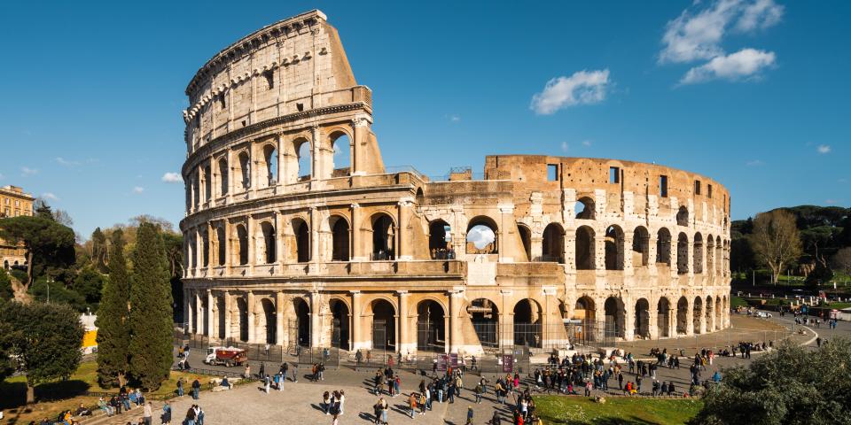 aerial stock photo of the Colosseum with tourists walking around