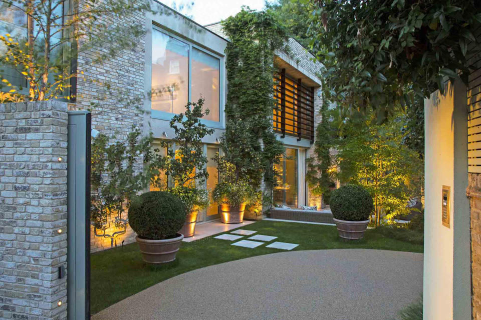 Lit up driveway with modern frontage and trees