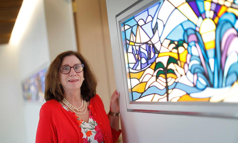 Rabbi Shira Joseph in front of the latest installation of art at Congregation Sha'aray Shalom in Hingham, a stained-glass piece by Lauren and Michael Teller.