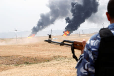 A member of the Kurdish security forces stands guard after explosions at two oil wells in Khabbaz oilfield, 20 km (12 miles) southwest of Kirkuk in Iraq, May 4, 2016. REUTERS/Ako Rasheed