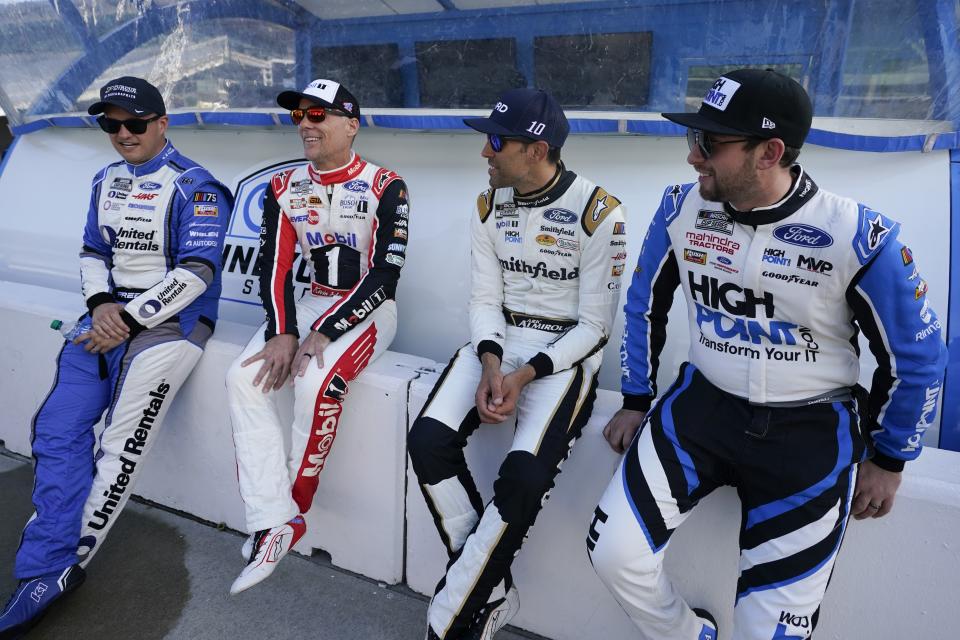 Ryan Preece, Kevin Harvick, Aric Almirola and Chase Briscoe, from left, talk before a practice session for the NASCAR Cup Series auto race at Indianapolis Motor Speedway, Saturday, Aug. 12, 2023, in Indianapolis. (AP Photo/Darron Cummings)