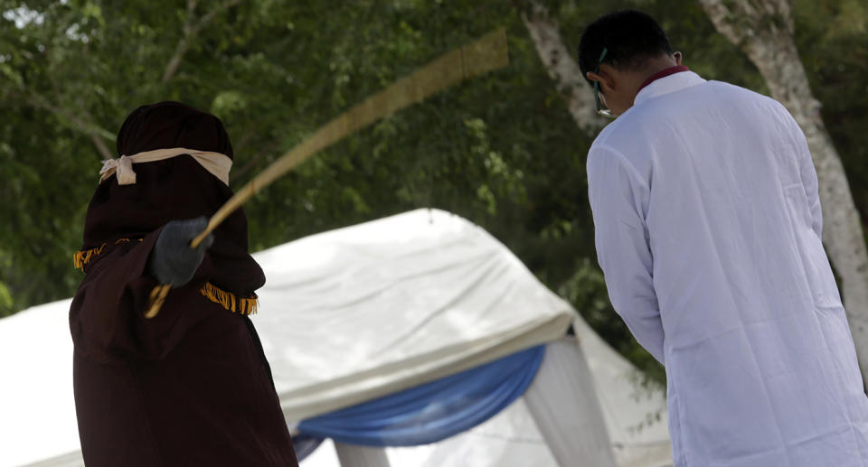 An man is caned in public for having sex outside of marriage in Banda Aceh.