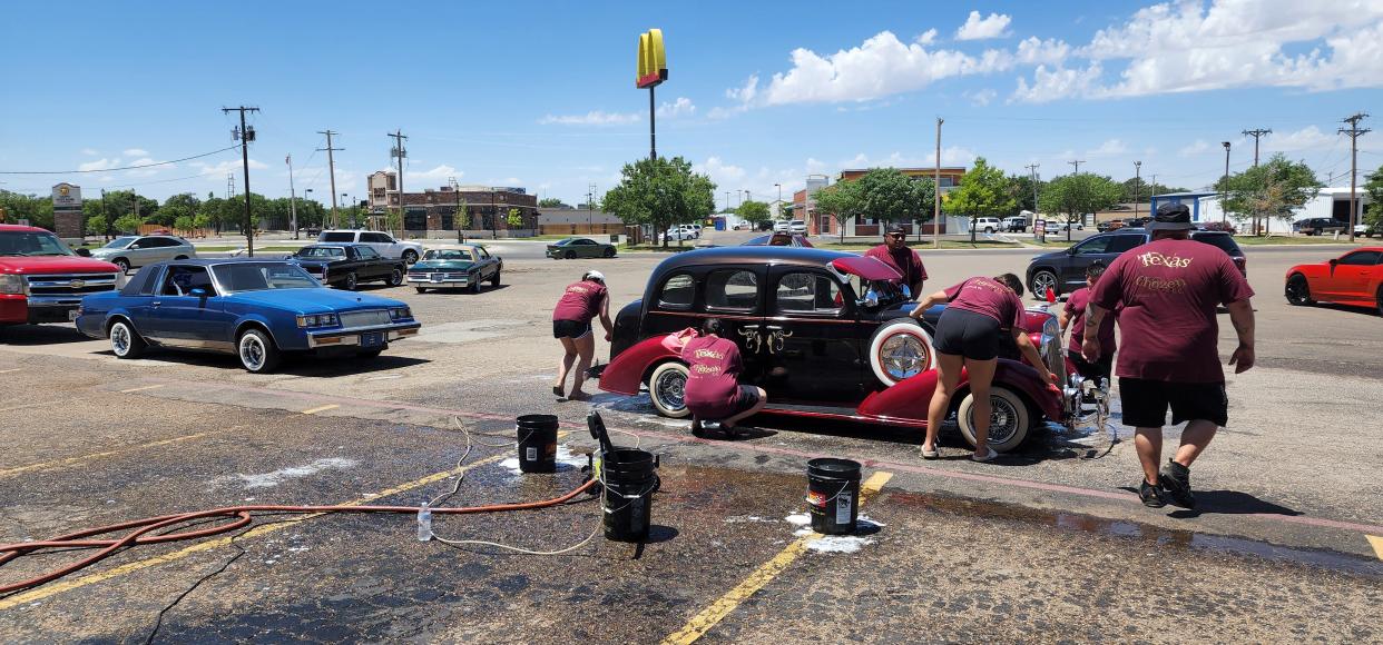 Members of the Texas Chozen Car Club work diligently together Saturday on a classic car during a car wash fundraiser for the Nicasio Frausto family at 4210 SW 45th Ave.