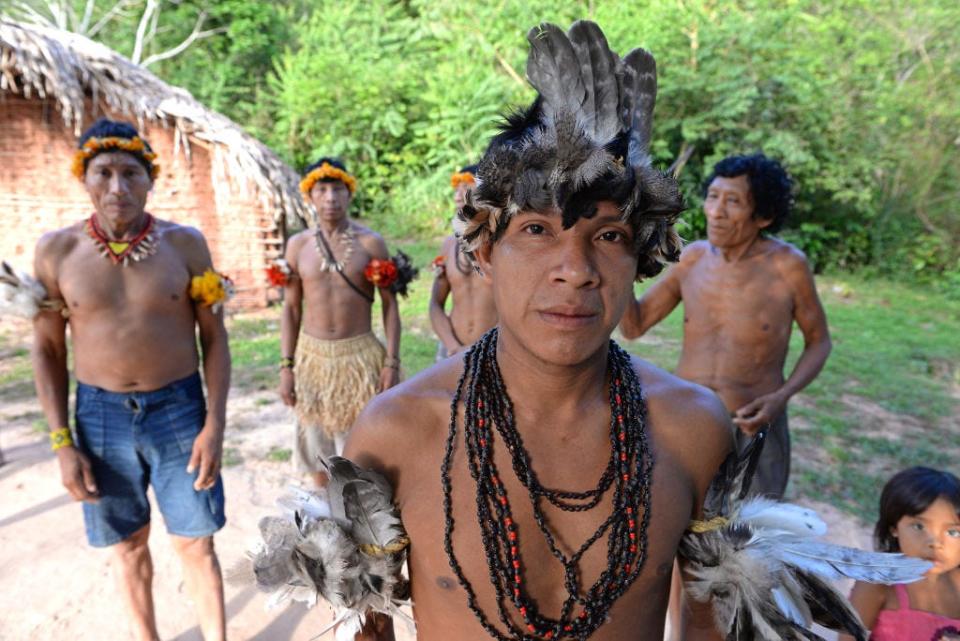 A young leader of the Awá tribe wears a turkey-feather headdress and other adornments in his village of Tiracambu, Maranhão, Brazil.