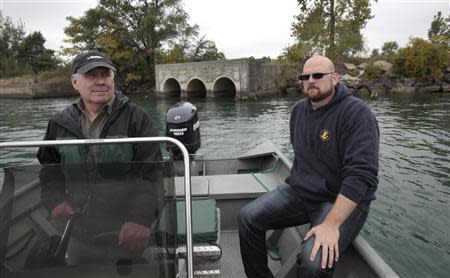 Robert Burns (L), a member of the environmental group 'Friends of the Detroit River', drives his boat along the Detroit River past Zug Island, along with Nicholas Schroeck, executive Director of Great Lakes Environmental Law Center, during an interview about The City of Detroit Water and Sewerage Wastewater Treatment Plant in Detroit, Michigan October 1, 2013. REUTERS/Rebecca Cook