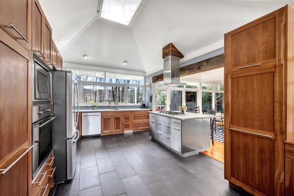 The reimagined kitchen features a large island, custom Cherry cabinetry, and all new stainless-steel appliances. Sliding glass doors connect the space to the backyard patio.