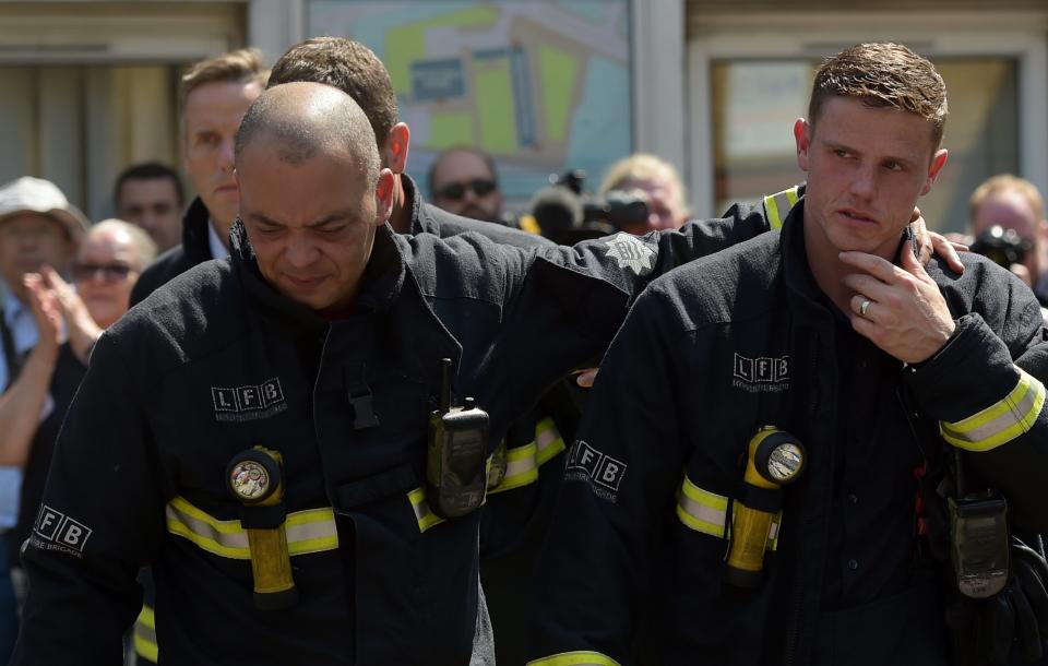 Firefighters at the memorial to the victims of the Grenfell Tower inferno  - Credit: CAMERA PRESS