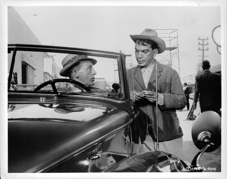 Cantinflas talks to a man in a car in a scene from the film 'Pepe', 1960. (Photo by Columbia Pictures/Getty Images)