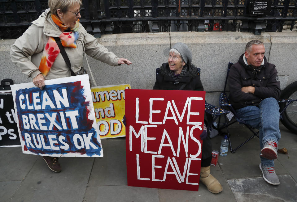 Pro-Brexit protestors show their posters in front of parliament in London, Wednesday, Oct. 23, 2019. Britain's government is waiting for the EU's response to its request for an extension to the Brexit deadline. (AP Photo/Frank Augstein)