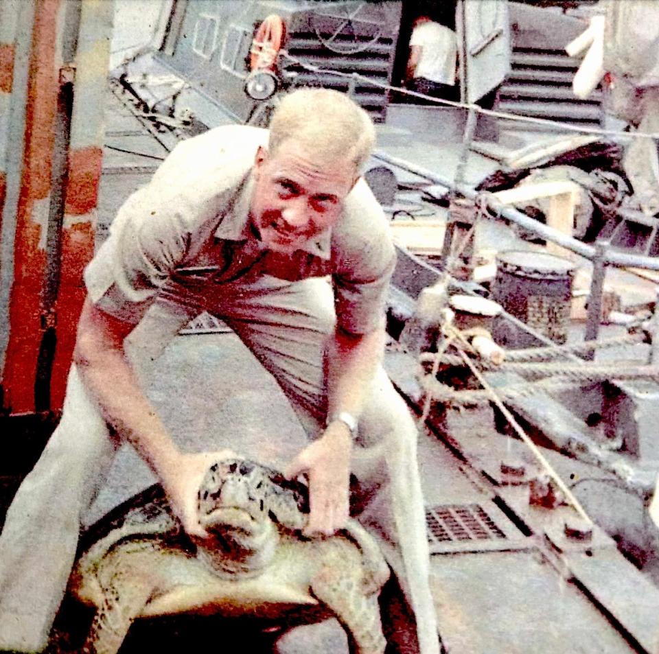 Lt. Daniel Ustick poses with a large snapping turtle at Cam Ranh Bay in 1967. His Swift Boat is on the right.