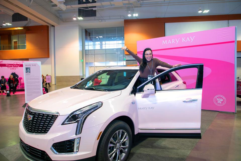 A Mary Kay conference attendee poses with one of the company's iconic pink Cadillacs at Music City Center.
