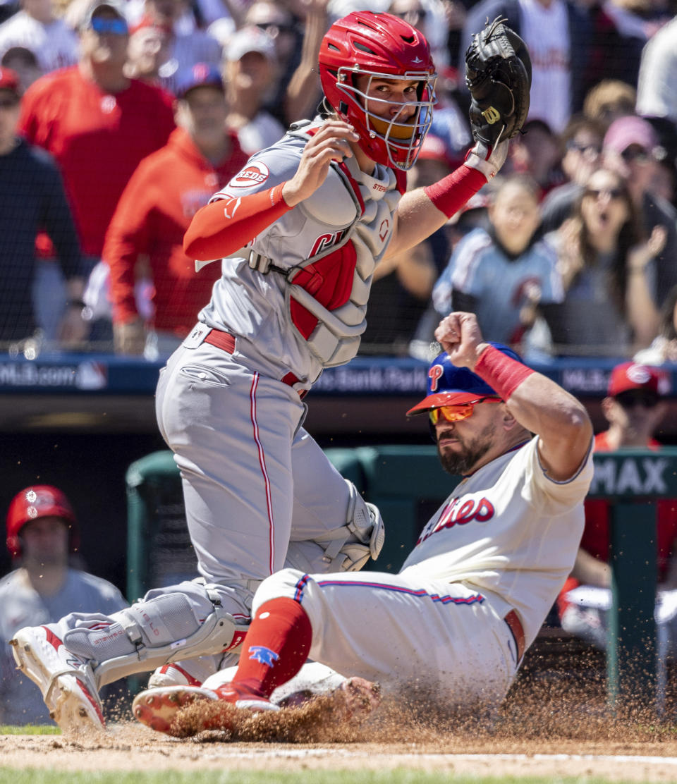 Philadelphia Phillies' Kyle Schwarber scores on an RBI by Nick Castellanos before Cincinnati Reds catcher Tyler Stephenson can make the tag during the first inning of a baseball game, Sunday, April 9, 2023, in Philadelphia. (AP Photo/Laurence Kesterson)