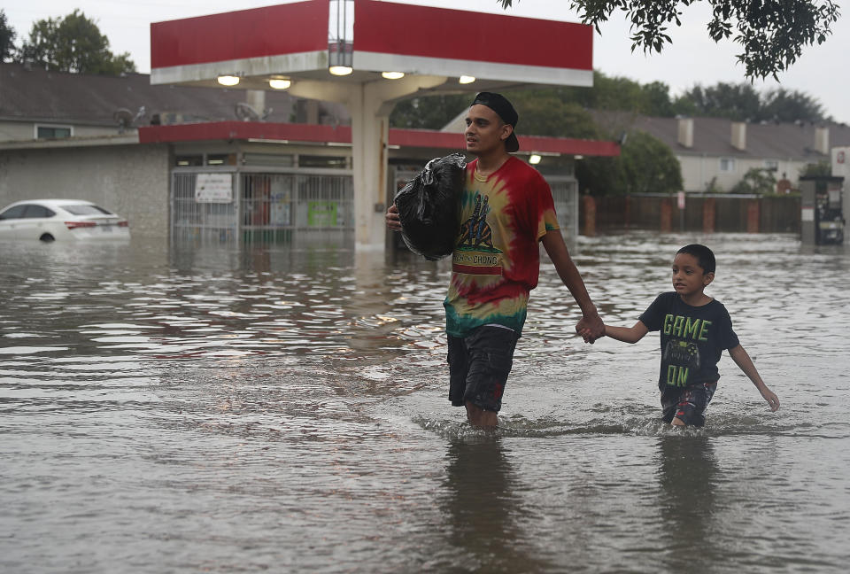 People walk down a flooded Houston street as they evacuate their homes Sunday after Hurricane Harvey hit. (Photo: Joe Raedle via Getty Images)