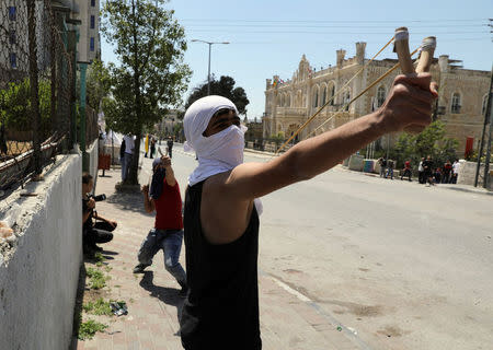 A Palestinian protester uses a slingshot to hurl stones towards Israeli troops during clashes following a protest in solidarity with Palestinian prisoners held by Israel, in the West Bank town of Bethlehem April 17, 2017. REUTERS/Ammar Awad