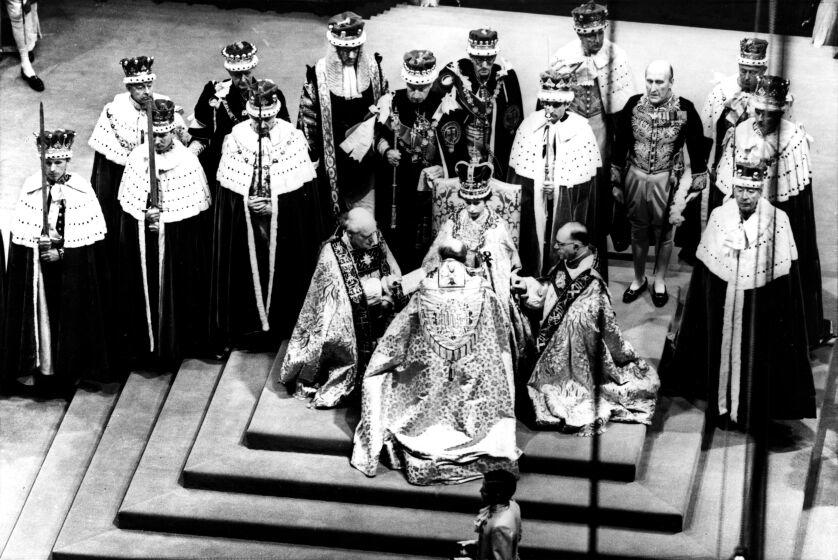 Britain's Queen Elizabeth II, seated on the throne, receives the fealty of the Archbishop of Canterbury, centre with back to camera, the Bishop of Durham, left and the Bishop of Bath and Wells, during her Coronation in Westminster Abbey, June 2, 1953. (AP Photo).