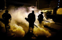 Members of a privately-funded non-governmental organization working with county officials disinfect a street to help curb the spread of the new coronavirus, during the dusk-to-dawn curfew, in the Kibera slum, or informal settlement, of Nairobi, Kenya Thursday, April 9, 2020. The new coronavirus causes mild or moderate symptoms for most people, but for some, especially older adults and people with existing health problems, it can cause more severe illness or death. (AP Photo/Brian Inganga)