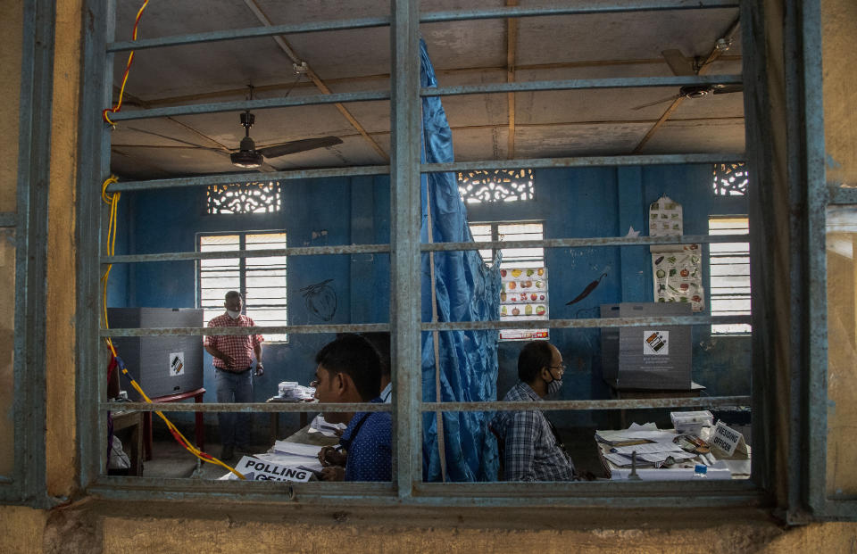 An Indian voter, left, leaves after casting his vote as a polling officer waits, right in a polling station during the third phase of assembly election in Gauhati, India, Tuesday, April 6, 2021. Voters in four Indian states and a union territory are casting their ballots, in elections seen as a test for Prime Minister Narendra Modi’s government which is battling the latest surge in coronavirus cases.(AP Photo/Anupam Nath)