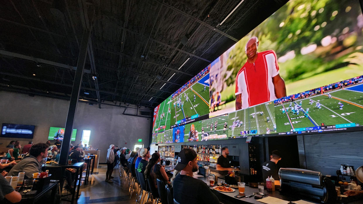  A <AXHUB 50-foot-wide display shows sports to bar patrons. . 