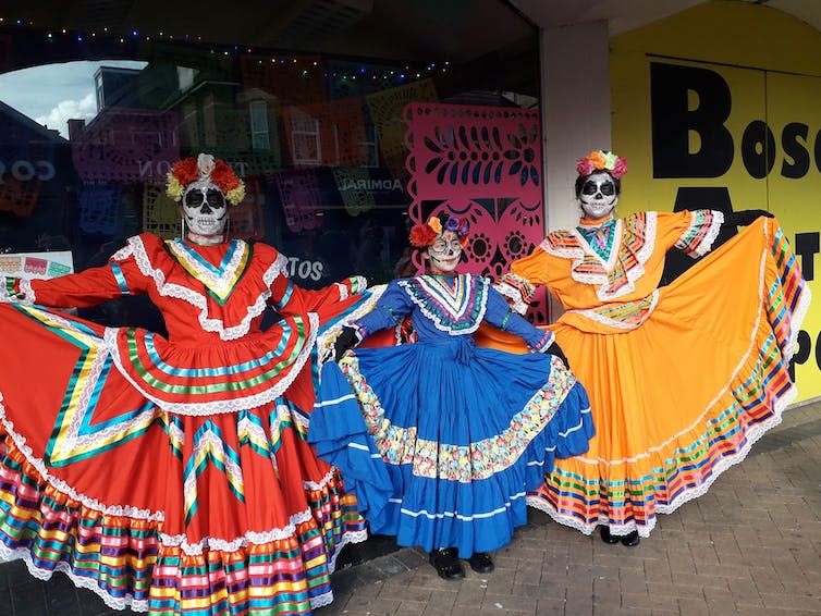 Three women dressed in colourful Day of the Dead costumes.