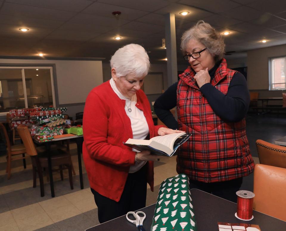 From left, Betty Harrell, program director and Sue Doyle from the Poughkeepsie branch of the American Association of University Women discuss a book while wrapping gifts on December 16, 2022. The AAUW received $900 from Holiday Helping Hand to purchase two books for each of the children currently living in Hudson River Lodging, transitional housing made available through Hudson River Housing.