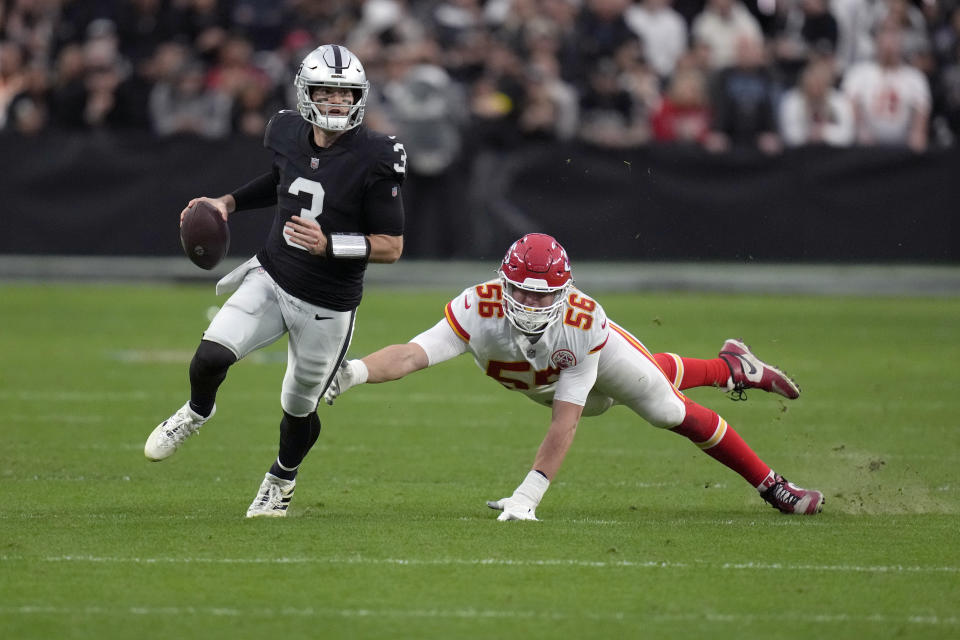 Las Vegas Raiders quarterback Jarrett Stidham (3) scrambles away from Kansas City Chiefs defensive end George Karlaftis (56) during the first half of an NFL football game Saturday, Jan. 7, 2023, in Las Vegas. (AP Photo/John Locher)