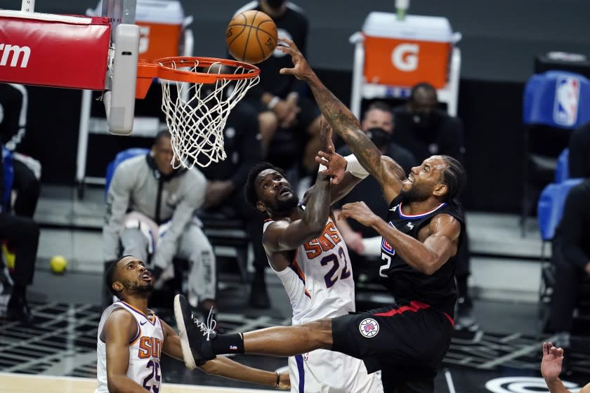 Los Angeles Clippers forward Kawhi Leonard, right, dunks over Phoenix Suns center Deandre Ayton (22) during the second half of an NBA basketball game Thursday, April 8, 2021, in Los Angeles. (AP Photo/Marcio Jose Sanchez)