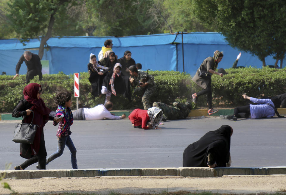 In this photo provided by Mehr News Agency, civilians try to take shelter in a shooting scene, during a military parade marking the 38th anniversary of Iraq's 1980 invasion of Iran, in the southwestern city of Ahvaz, Iran, Saturday, Sept. 22, 2018. Gunmen attacked the military parade, killing at least eight members of the elite Revolutionary Guard and wounding 20 others, state media said. (AP Photo/Mehr News Agency, Mehdi Pedramkhoo)