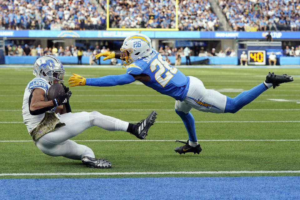 Detroit Lions wide receiver Amon-Ra St. Brown (14) makes a catch nex to Los Angeles Chargers cornerback Asante Samuel Jr. (26) during the first half an NFL football game Sunday, Nov. 12, 2023, in Inglewood, Calif. (AP Photo/Gregory Bull)