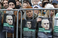 People hold portraits with signs read "Freedom to Yevgeny Kovalenko", center, and "Freedom to Ivan Podkopaev", left and right, during a rally to support political prisoners in Moscow, Russia, Sunday, Sept. 29, 2019. (AP Photo/Dmitri Lovetsky)