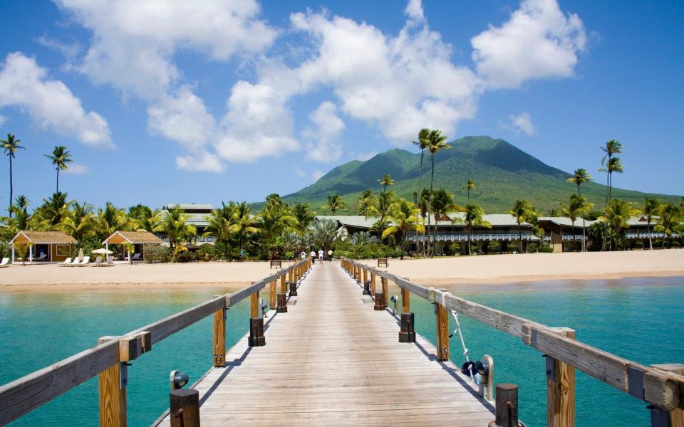 Stunning Pinney's beach with Coconut Palms, and the Volcano in the distance, at Nevis. Caribbean - Getty