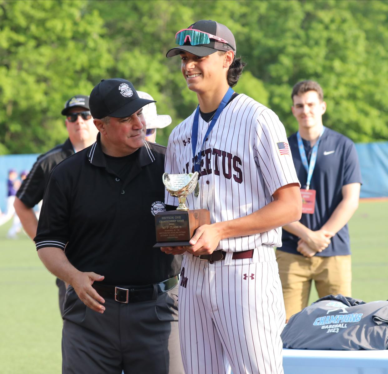 Albertus Magnus pitcher Patrick Veintimilla is presented a trophy as players celebrate after defeating Croton, during the Albertus Magnus vs. Croton-Harmon Section One Class B baseball championships at Purchase College in Purchase, New York, Mat 27, 2023. Albertus Magnus defeated Croton-Harmon, 4-1.