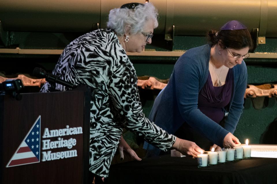Cantors Wendy Siegel, left, of Temple Emanuel of Marlborough, and Vera Broekhuysen, of Congregation Beth El of Sudbury, light memorial candles during the induction ceremony for the World War II-era German rail car at the American Heritage Museum in Hudson, Jan. 19, 2024.