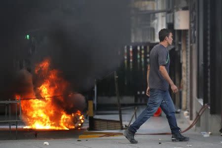 A man walks past a burning barricade after clashes broke out while the Constituent Assembly election was being carried out in Caracas, Venezuela, July 30, 2017. REUTERS/Carlos Garcia Rawlins
