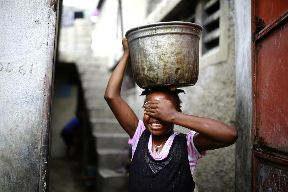 In this May 31, 2019 photo, a girl carries water six months after a massacre in the La Saline slum of Port-au-Prince, Haiti. The weeklong massacre began on Nov. 13, when men with guns and machetes broke into homes, killing at least 21 people and raping several women. (AP Photo/Dieu Nalio Chery)