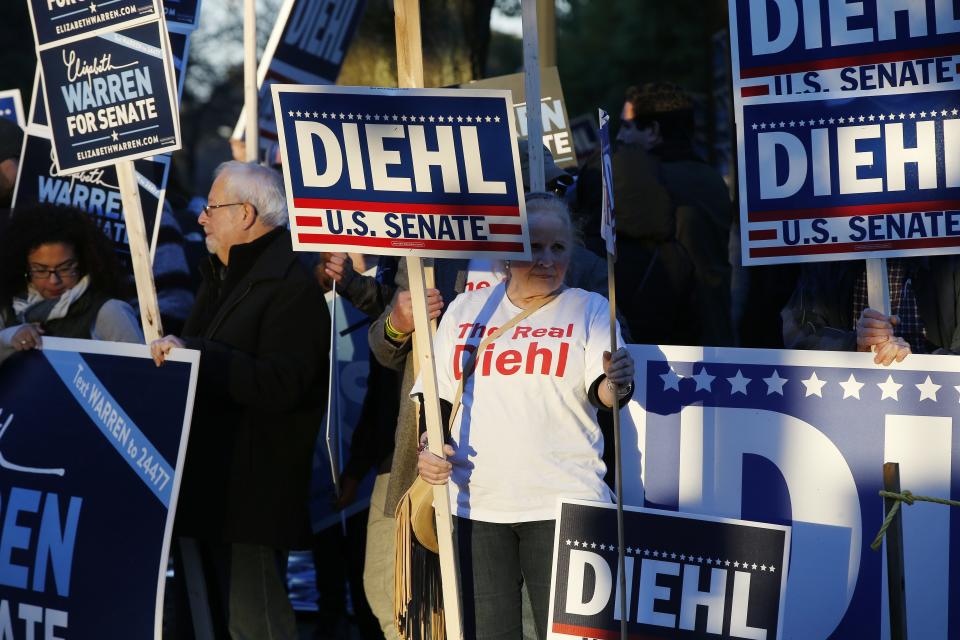 Supporters of Sen. Elizabeth Warren and her opponent Geoff Diehl holds signs before a debate between the two candidates in Boston, Friday, Oct. 19, 2018. (AP Photo/Michael Dwyer)