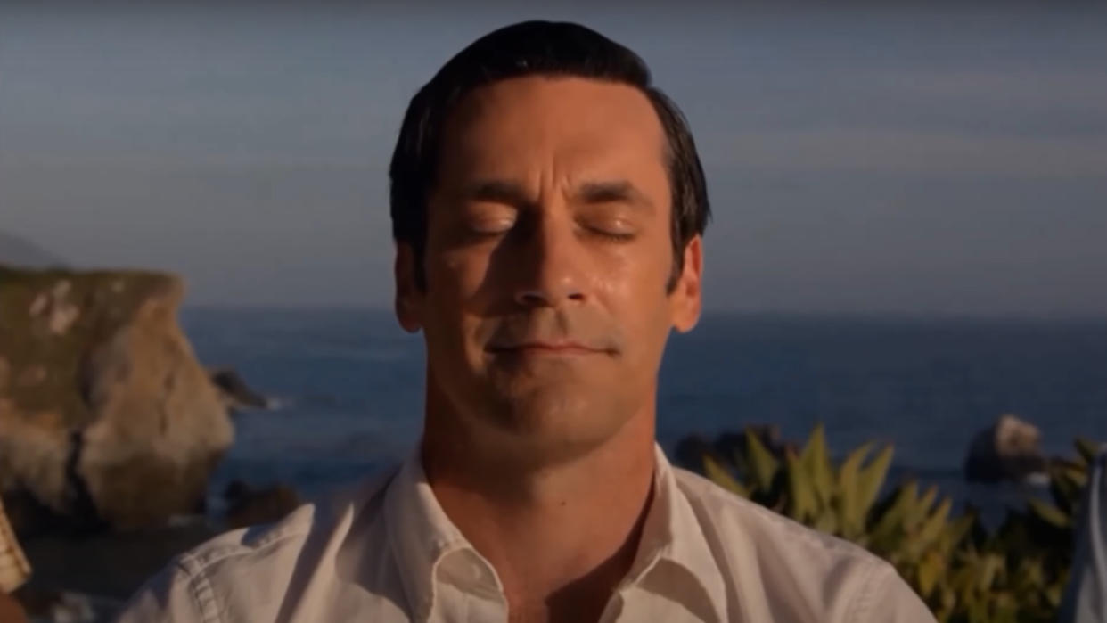  Jon Hamm sits in nature with a smile in Mad Men. 