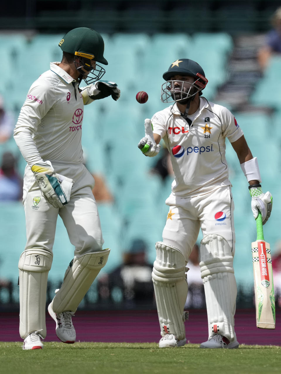 Pakistan's Mohammad Rizwan, right, throws the ball to Australia's Alex Carey on the fourth day of their cricket test match in Sydney, Saturday, Jan. 6, 2024. (AP Photo/Rick Rycroft)