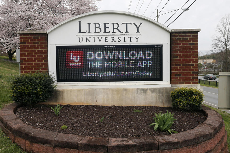 FILE - In this March 24 , 2020, file photo, a sign marks the entrance to Liberty University in Lynchburg, Va. The university, led by Jerry Falwell Jr., is pushing for criminal trespassing charges to be lodged against two journalists who pursued stories about why the evangelical college has remained partially open during the coronavirus outbreak. (AP Photo/Steve Helber, File)