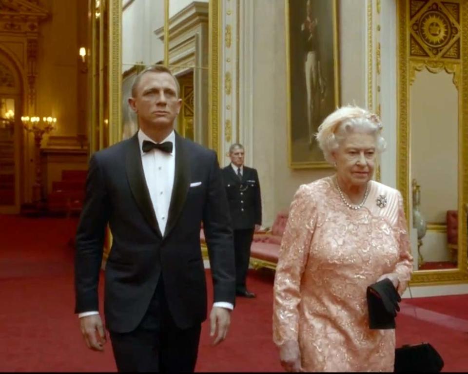 La Reina Isabel II descendió de su majestad para ofrecer a sus súbditos y a las millones de personas que siguieron la inauguración de los Juegos Olímpicos de Londres 2012 unos minutos de divertimento. La monarca del Reino Unido apareció en las gigantescas pantallas del Estadio Olímpico no en su grave papel de jefa de Estado, sino como personaje en un disparatado cortometraje que inauguró (y seguramente cerró) su carrera como actriz. Isabel II recibió a James Bond –o sea, al actor Daniel Craig– en una de las habitaciones del Palacio de Buckingham, antes de subir a un helicóptero con el célebre agente 007. La nave sobrevoló la capital británica hasta colocarse encima del estadio. En ese instante, y frente a la vacilación de Bond, su majestad –o más bien un doble– se lanzó en paracaídas. Este performance fue uno de los extravagantes momentos de la inauguración de los juegos estivales, animados también por segmentos de humor como el protagonizado por Mr. Bean, al piano junto a la Orquesta Sinfónica de Londres.